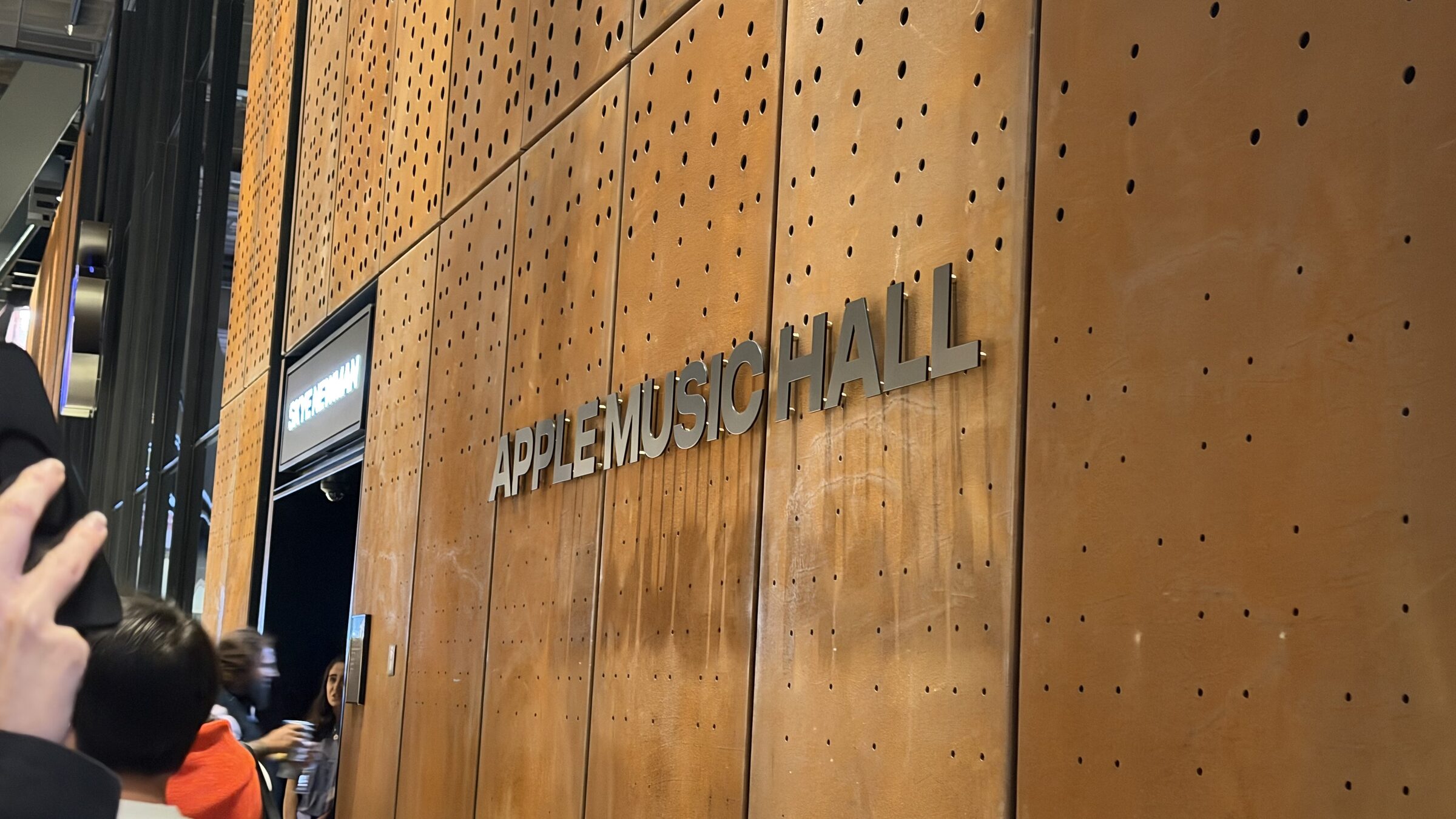 The Apple Music Hall entrance: silver letters on rust-coloured perforated metal panels, with Skye Newman's name lit above the door