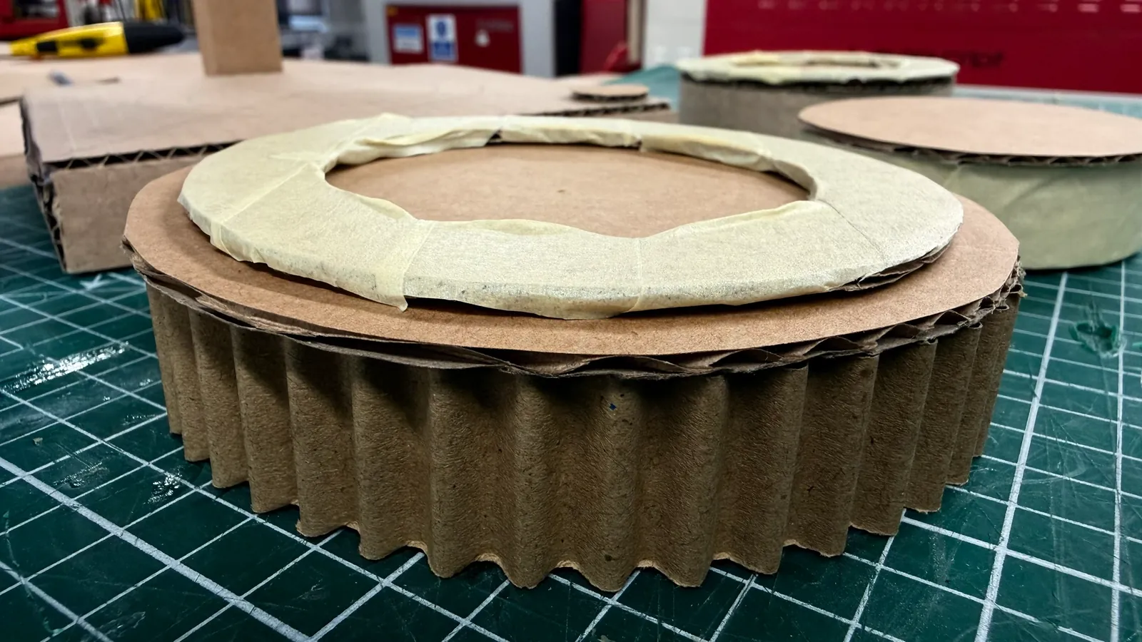 Cardboard coaster prototype with a raised cardboard ring on a cutting mat