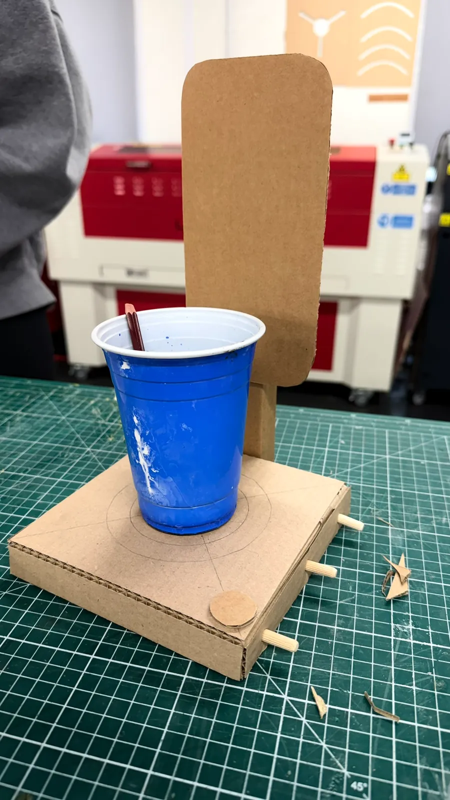 Early wooden base with a cardboard screen mock-up and a blue plastic cup