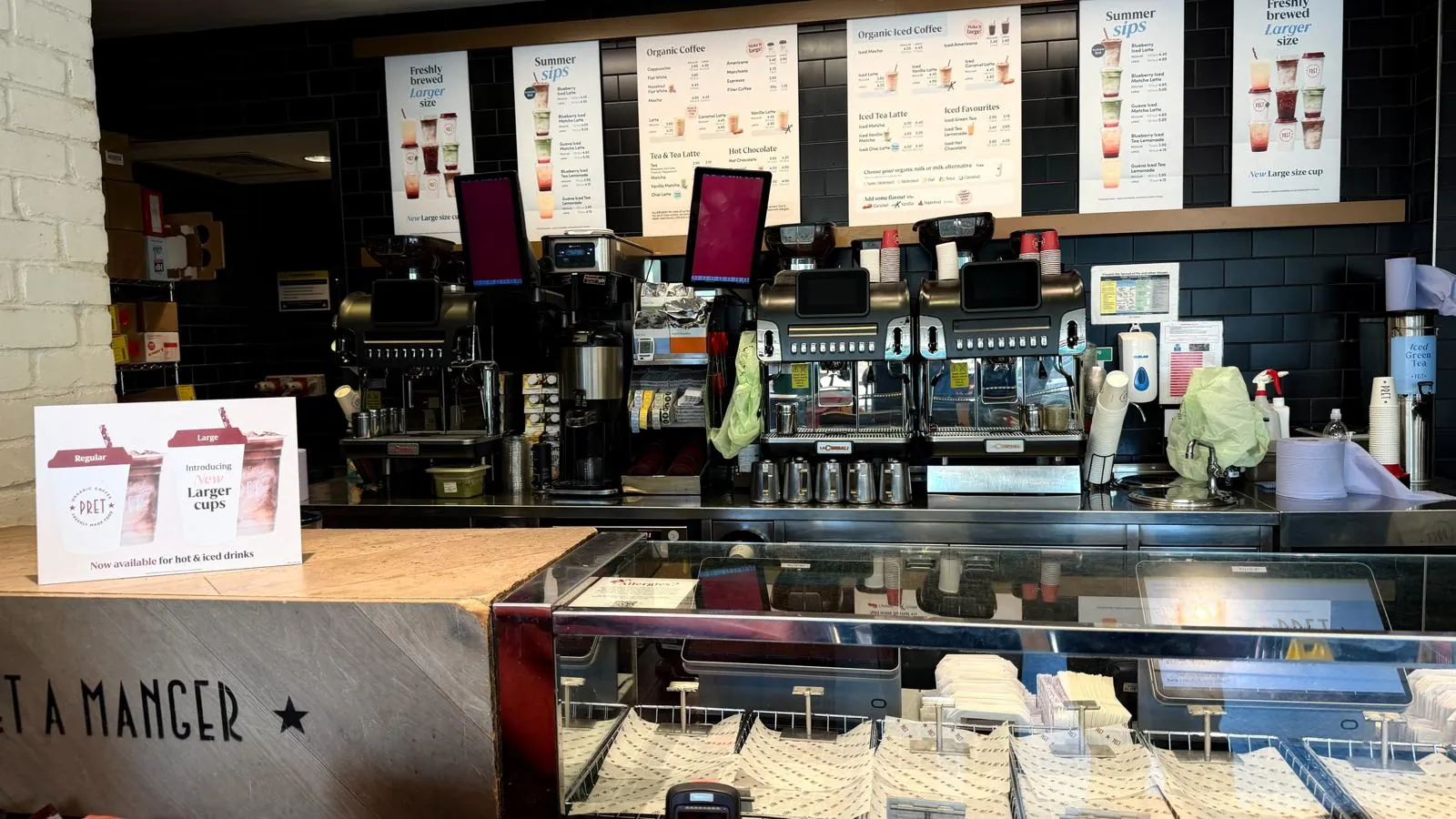 A busy chain café counter with several espresso machines and menu boards