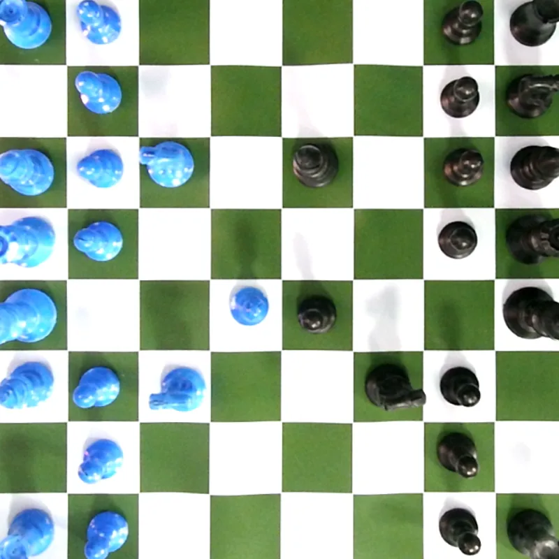 Overhead webcam frame of a green and white chessboard, warped flat, with blue pieces on one side and black pieces on the other, mid-game