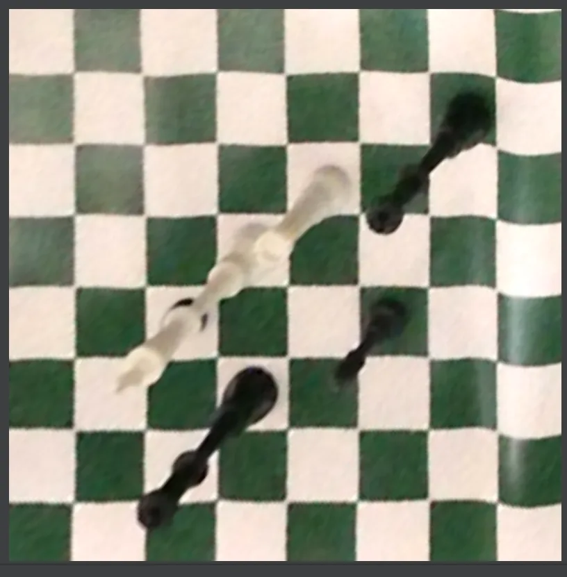 A warped board image taken from a low side angle: black and white pieces smeared diagonally across several squares