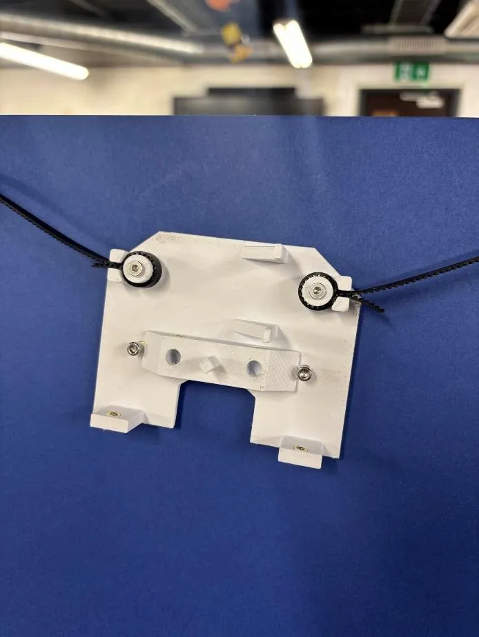 Close-up of the printed white pen carriage hanging from two belts on a blue board