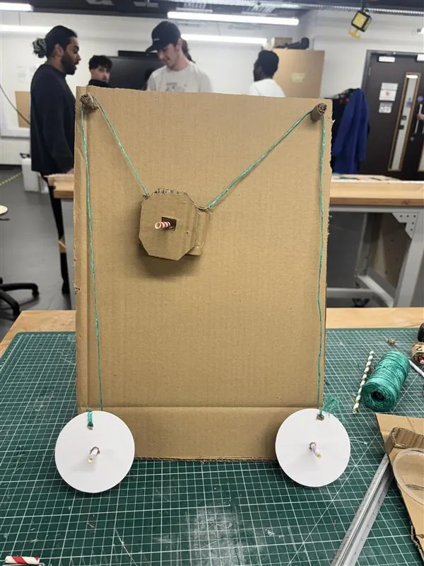 Front of cardboard model V1 with a cardboard carriage and motors at the bottom corners